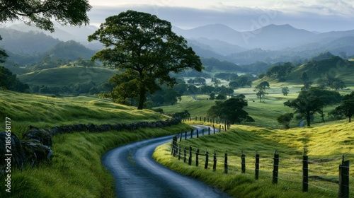 Serene countryside landscape with winding road, lush green fields, rolling hills, and distant mountains under soft morning light