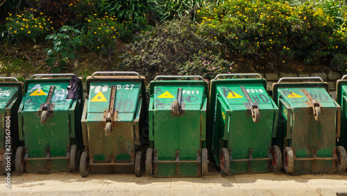 Obraz na plátně Green garbage bins lined up on sunny street
