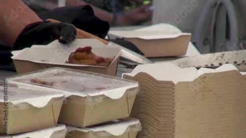 Close-up of chefs preparing and packing food at an open street kitchen