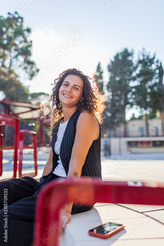 Portrait of a happy young woman with natural curly hair. A confident lady in the city background.a girl smiling in the city on a sunny day.