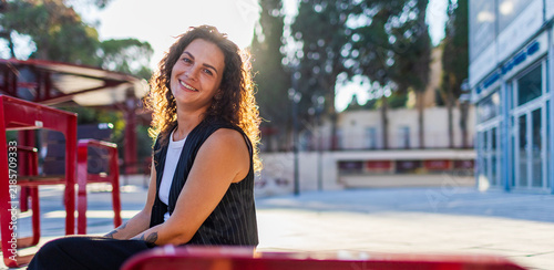 Portrait of a happy young woman with natural curly hair. A confident lady in the city background.a girl smiling in the city on a sunny day.