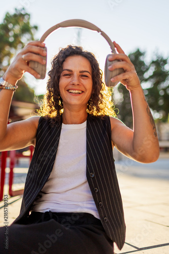 Young woman enjoys music in wireless headphones in a bustling city. girl in headphones.