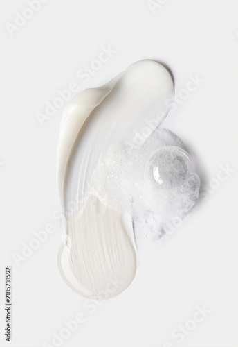 samples of cosmetic care products smear of cream and serum texture on a light background