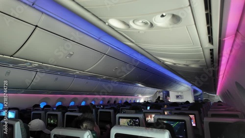 Passengers sit inside a modern airplane cabin with colorful lighting.