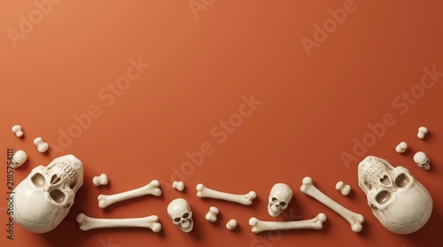 Human skulls and bones arranged as a frame on an orange background