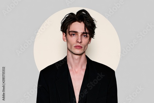 Stylish Young Man in Black Blazer with Modern Hairstyle Against Minimalist Background