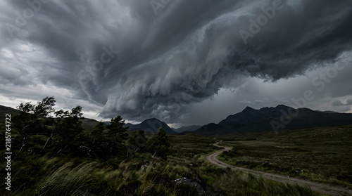 Dramatic dark storm clouds gathering over a rugged mountain landscape in Scotland.