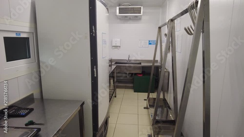 The area shows a commercial kitchen with stainless steel counters and equipment designed for food preparation. There is a scale on the counter for weighing ingredients and a sink for cleaning. 