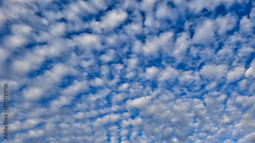 Foto Scattered puffy altocumulus clouds spread evenly across a bright blue sky background on a sunny day