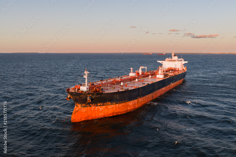 Fototapeta premium High angle aerial drone shot of a large empty cargo ship riding high in ballast on the open waters of the Baltic Sea during sunset.
