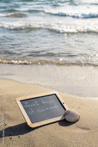 Cuadro en lienzo Chalkboard reading “Last days of Summer” on a sandy beach beside a seashell and ocean waves, symbolizing the end of vacation and return to everyday life