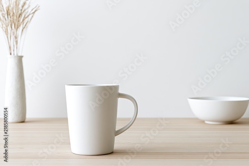 White ceramic mug, bowl, and dried grass in a vase on wood