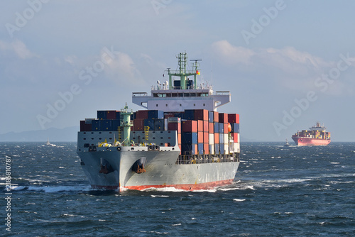 Container ship sailing through rough seas with stacked shipping containers