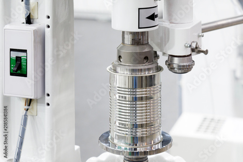 automatic can seaming machine seals metal tin can in modern packaging and food processing factory. aluminum cans processed on conveyor belt machine in canned food manufacturing. industrial technology