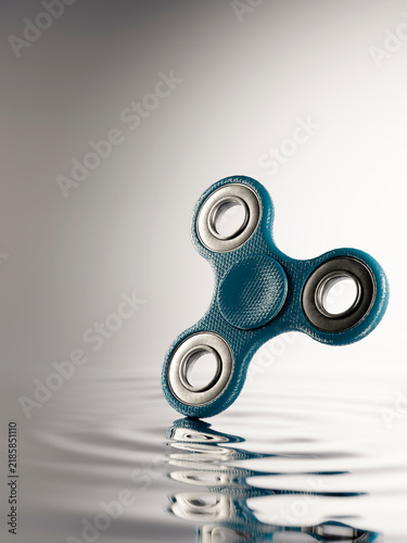 Fotografía Blue fidget spinner creating ripples on calm water surface, a symbol of focus