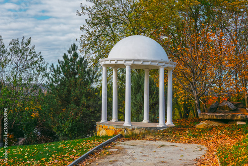Konstfotografi Rotunda stands beneath autumn foliage in a park, its white dome and columns rising above a stone base