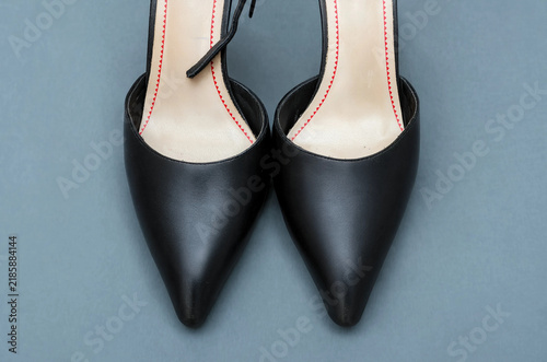 Elegant black leather pointed-toe slingback high heel pumps top view on blue-gray background with copy space