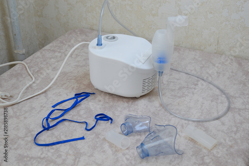 Medical compressor nebulizer machine with air tubing, inhalation chamber, masks, and accessories laid on a table. Respiratory treatment, asthma healthcare equipment, and medical technology concept