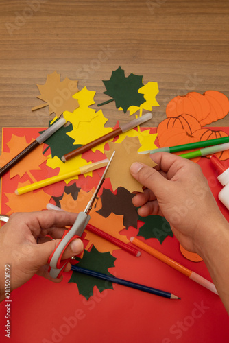 Top view of male hands engaging in an autumn craft activity with various creative materials on a work table