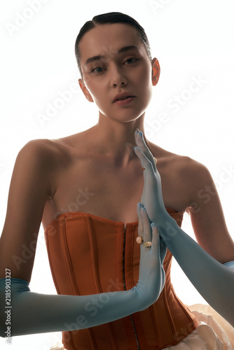 фотографія Fashion portrait of a young woman in a terracotta corset and blue gloves