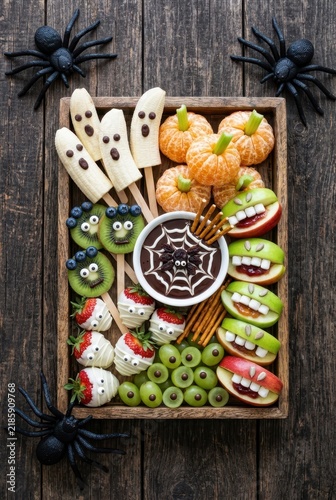 Healthy Halloween Fruit Platter with Banana Ghosts, Tangerine Pumpkins, and Apple Monsters on Wooden Background