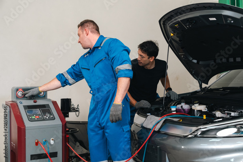 Foto Electric vehicle battery car service Automotive technician in blue coverall oper