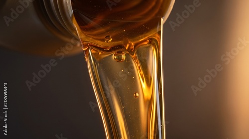 Amber Viscous Engine Oil Being Poured From A Container Providing Smooth Lubrication And Protection For High Performance Automotive Machinery