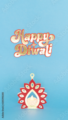 Canvas Print Glowing diya with peacock design against soft blue background