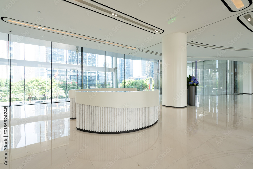 Obraz premium Modern minimalist office reception area with curved white desk and large windows