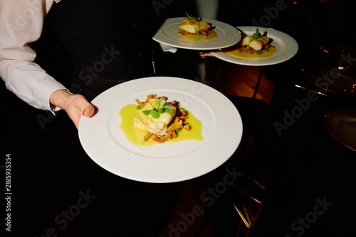 Fine Dining Dish Served by Waiter on Elegant White Plates in Restaurant