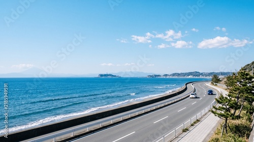 Scenic coastal highway along the blue ocean in kamakura, japan, with enoshima island visible in the distance under a clear sunny sky