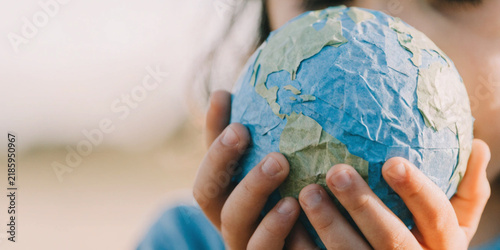 Global warming and changes in climate and the environment with a child hands holding a paper model of the world