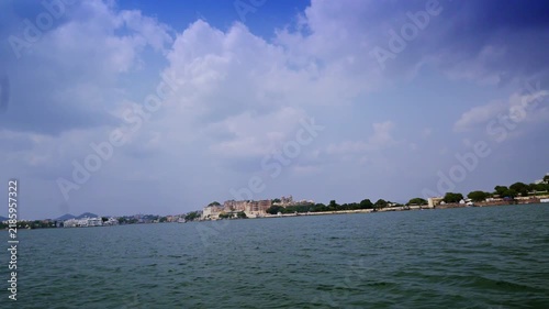Distant City Palace and Udaipur's tree-lined shore appear across the wide open water of Lake Pichola.