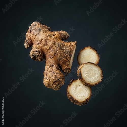 Fresh Ginger Root With Slices Isolated On Dark Background