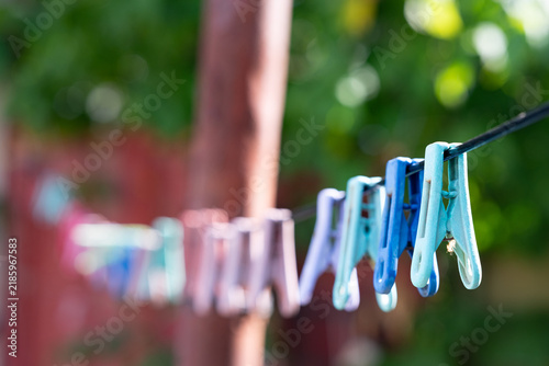 Quadro su tela A row of colorful plastic clothespins hanging on a clothesline outdoors with a s