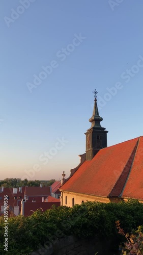 Historic Petrovaradin church spire with a red tiled roof stands against a clear evening sky in Novi Sad, Serbia