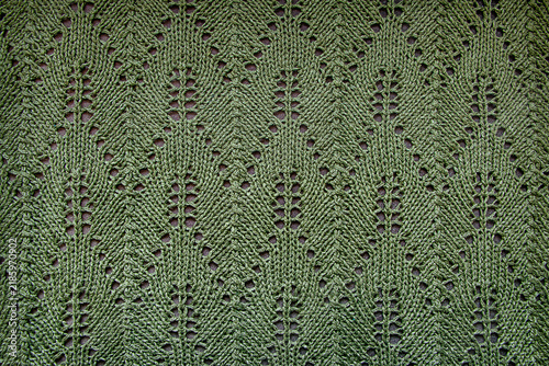 A close-up of the texture of the knitted fabric. A green background with openwork knitted patterns