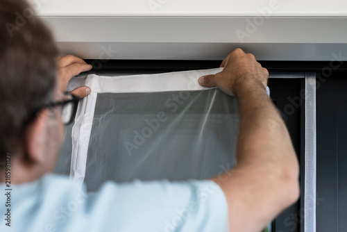 Canvastavla Person securing a white mosquito screen into the window frame, illustrating precise handwork in home tasks and maintenance