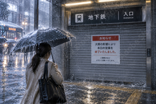 豪雨で閉鎖された地下鉄入口に立ち尽くす女性