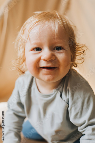 Cute little baby crawling on a soft carpet at home and looking directly at the camera. Adorable toddler exploring the home interior in natural light, representing early childhood, development