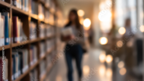 Blurred view of a female student holding books and walking along tall bookshelves in a library