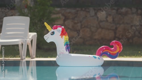 Pool with unicorn float and chair in sunny backyard during summer afternoon