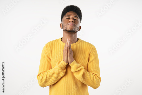 Foto Close up portrait of young man praying with hands clasped isolated over white ba