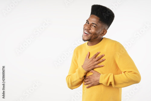 Grateful African man holding hands on chest near heart isolated over white background, emotional young male expressing gratitude, appreciation, sincerity, kindness and heartfelt thankfulness concept