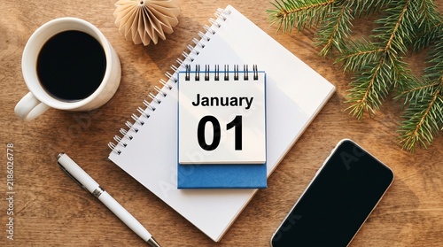January 1st calendar on a notebook with coffee and mobile phone on a wooden desk with setup displays january