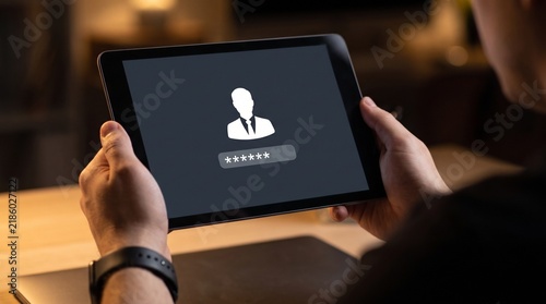 Person holding a tablet displaying a user account login screen with password field at night with tablet