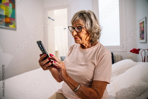 Senior woman using smartphone in bedroom