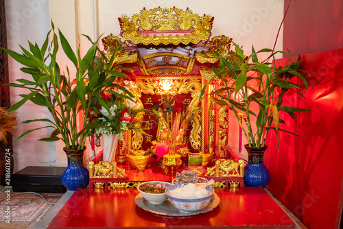 Bild auf Leinwand Golden spirit house shrine glows softly indoors surrounded by green plants and s
