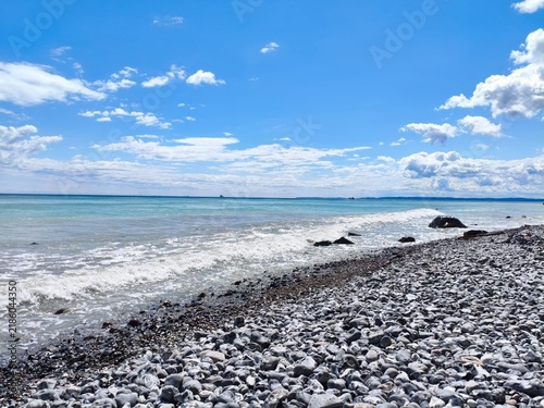 Принти на полотні Wide view facing bright azure aquatic expanse from textured grey bank