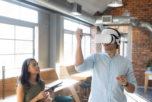 Diverse coworkers demonstrating VR headset interaction in coworking office with tablet and stylus